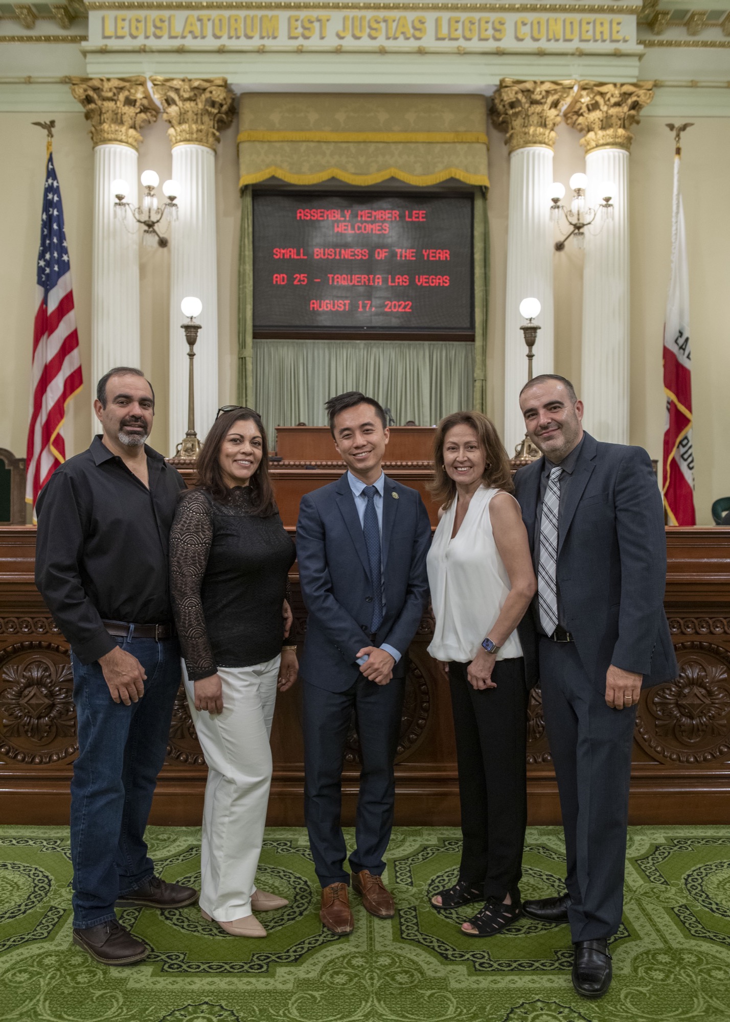 Standing on Assembly floor with screen reading - Taqueria Las Vegas AD 25 Business of the Year