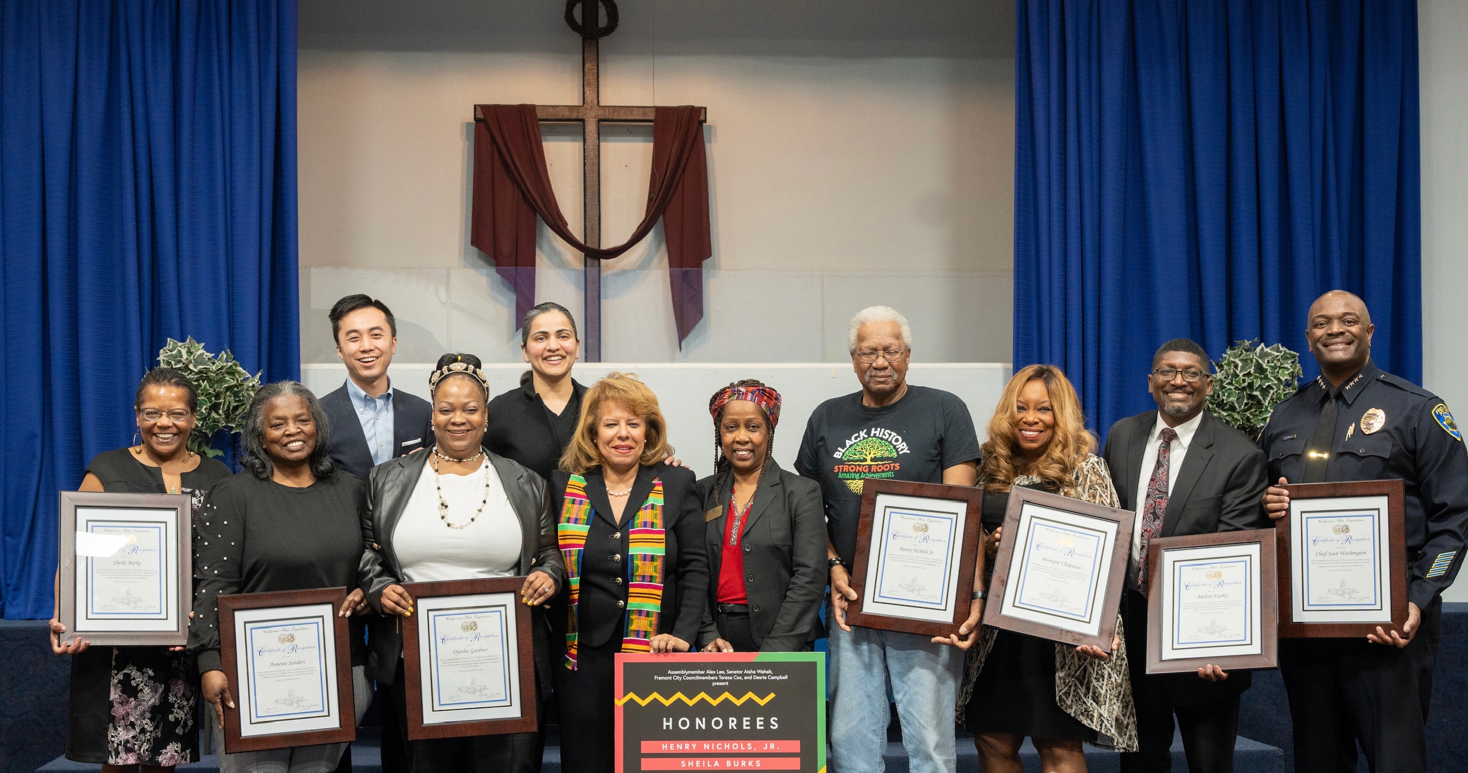 Group of honorees standing on stage with plaques 