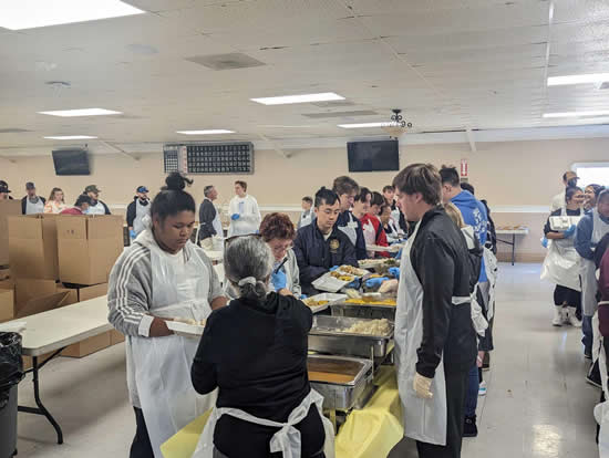 Asm. Lee with multiple volunteers preparing meals at long tables
