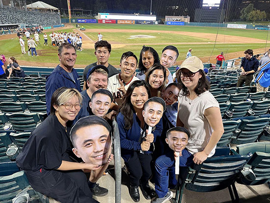 Assemblymember Lee in the center of a group of fans at the legislative softball game