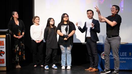 Asm. Lee with students and interpreters on stage
